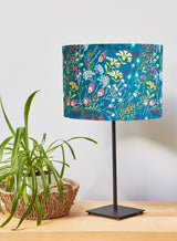 Teal fabric lampshade with vibrant wildflower print. Pink, orange, yellow and green leaves and flowers against a dark green background. Beautiful when lit